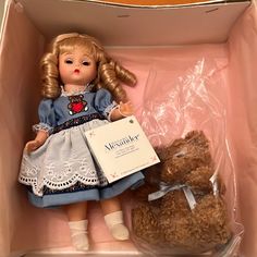 a doll and a teddy bear in a box