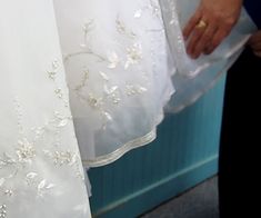 two people standing next to each other in front of a wall with white dresses on it