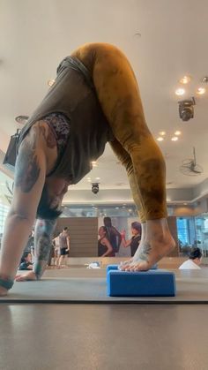 a man standing on top of a blue block with his feet in the air as he does a handstand