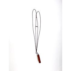 a red object hanging from the side of a white wall next to a black cord