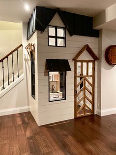 a doll house is in the middle of a hardwood floored room with stairs and railings