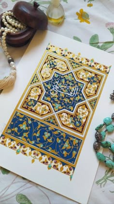 an ornate blue and yellow design on paper next to beads, necklaces and other items