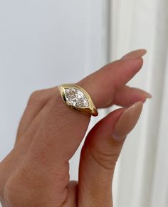 a woman's hand holding a yellow gold ring with a diamond in the middle