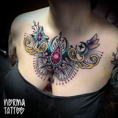 a woman's chest with an intricate tattoo design on it