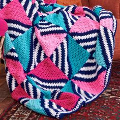 a colorful crocheted bag sitting on top of a rug next to a couch