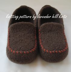 a pair of brown slippers with red stitching on them sitting on a white surface