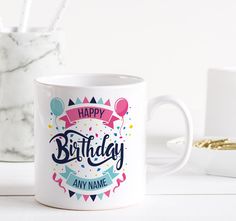 a white coffee mug with the words happy birthday on it and balloons in the background