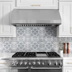 a stove top oven sitting inside of a kitchen next to white cupboards and counter tops