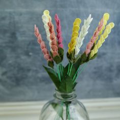 a vase filled with colorful flowers sitting on top of a wooden table next to a gray wall