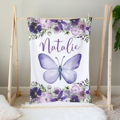 a purple and white butterfly with flowers on it that says natlie next to a plant