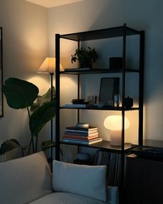 a living room filled with furniture and a lamp next to a book shelf full of books