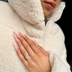 a woman wearing a white coat and diamond ring