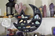 a black metal moon and star decoration on a shelf next to other rocks, crystals and candles