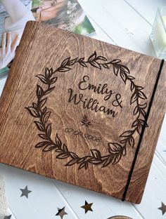 an engraved wooden guest book on a table next to some photos and other personal items