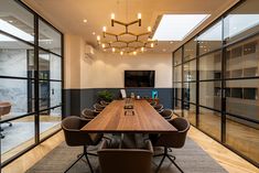 a conference room with large wooden table surrounded by brown chairs and glass doors that lead to an outside patio