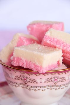 small pieces of pink and white cake in a bowl on top of a saucer