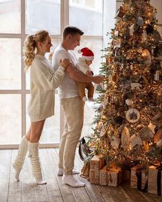 a man and woman standing next to a christmas tree