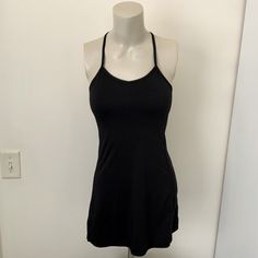 a woman's black tank top on a mannequin head stand in front of a white wall