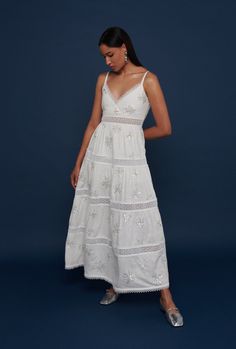 This V neck maxi dress features delicate lace panels and trim at the neckline and hem, as well as a flattering silhouette and embroidered palm trees made with small sequins, beads and pearls.  A perfect example of Waimari’s understated elegance. Summer Embellished Floor-length Midi Dress, Floor-length Embellished Midi Dress For Summer, White Floor-length Maxi Dress With Floral Embroidery, Elegant Summer Maxi Dress With Cutwork Hem, Elegant Embroidered Dress With Lace Work For Summer, White V-neck Maxi Dress With Lace Trim, Midi Length Dresses With Cutwork Hem For Vacation, Summer Maxi Dress With Cutwork Hem, White Elegant Maxi Dress With Lace Trim