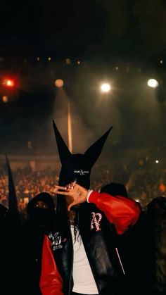 a person wearing a mask and jacket at a concert