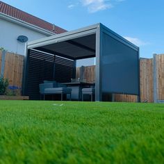 an outdoor living area with green grass and a covered patio in the middle of it