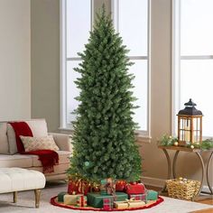 a christmas tree in the middle of a living room with presents on the floor next to it