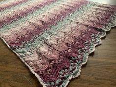 a crocheted rug is laying on the floor with wood floors in front of it