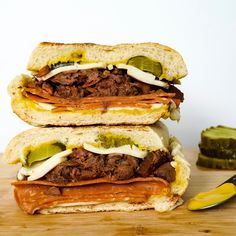 two sandwiches stacked on top of each other with pickles next to them and a knife