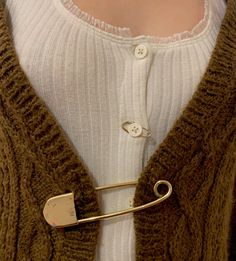 a close up of a person wearing a sweater with a tie clip on their lapel