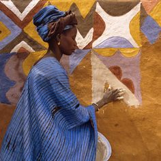 a woman in a blue dress painting on the side of a wall