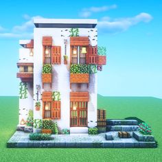 a tall white building with lots of windows and plants growing on the balconies