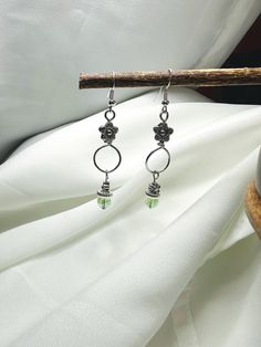 Beautiful silver handmade dangle earrings. These are very elegant. The bead is a sea green. Just a hint of color. The design is unique. These will be a great gift or just a gift for yourself. Silver Dangle Earrings For May Birthstone, Silver Single Earring For May Birthstone, Green Minimalist Sterling Silver Earrings, Minimalist Green Sterling Silver Earrings, Handmade Silver Dangle Flower Earrings, Green Dangle Crystal Earrings, Handmade Green Crystal Metal Earrings, Green Sterling Silver Crystal Earrings, Handmade Silver May Birthstone Earrings