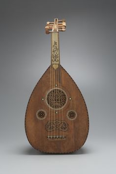 an old wooden instrument with intricate designs on it's body and neck, sitting against a gray background