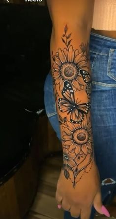 a woman's arm with sunflowers and butterflies tattooed on the side of her leg