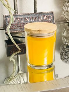 a glass cup filled with yellow liquid sitting on top of a metal shelf next to a sign