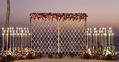 an outdoor wedding setup with candles and flowers on the beach at dusk, along with palm trees