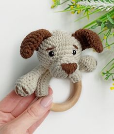 a hand holding a crocheted dog ring on top of a table next to flowers