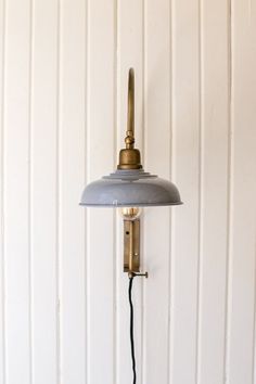 an old fashioned wall lamp with a cord attached to the light fixture in front of a white painted wall