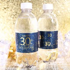 two bottled water bottles sitting next to each other on top of a table covered in gold glitter