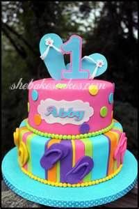 a colorful birthday cake with the number one on it's top tier and decorations