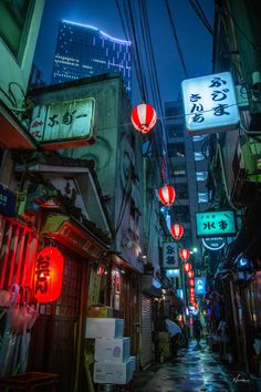 an alleyway with chinese lanterns hanging from it's sides in the city at night