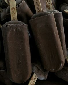 chocolate ice cream pops sitting on top of each other with wooden sticks sticking out of them