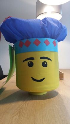 a lego head with a blue hat on it's head sitting on top of a wooden table