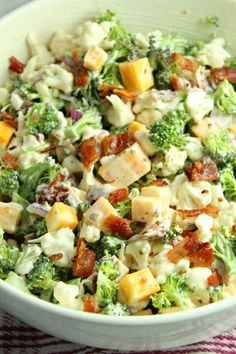 a white bowl filled with broccoli and chicken salad on top of a red and white checkered table cloth