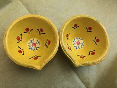 two yellow bowls with designs on them sitting next to each other