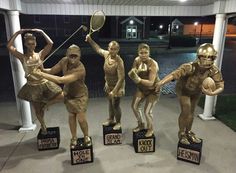 four statues of women in sports uniforms holding tennis rackets