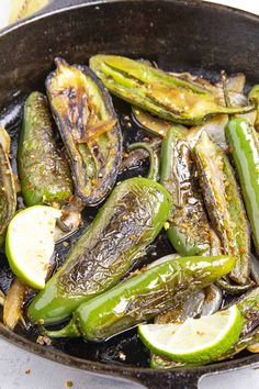 a skillet filled with green peppers and sliced up lemons on top of a table