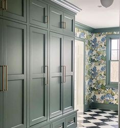 a kitchen with green cabinets and checkered flooring in front of a large window