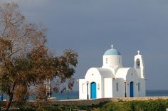 a white church with blue domes near the ocean