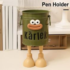 a wooden toy with a green bucket on it's head and legs, standing in front of bookshelves